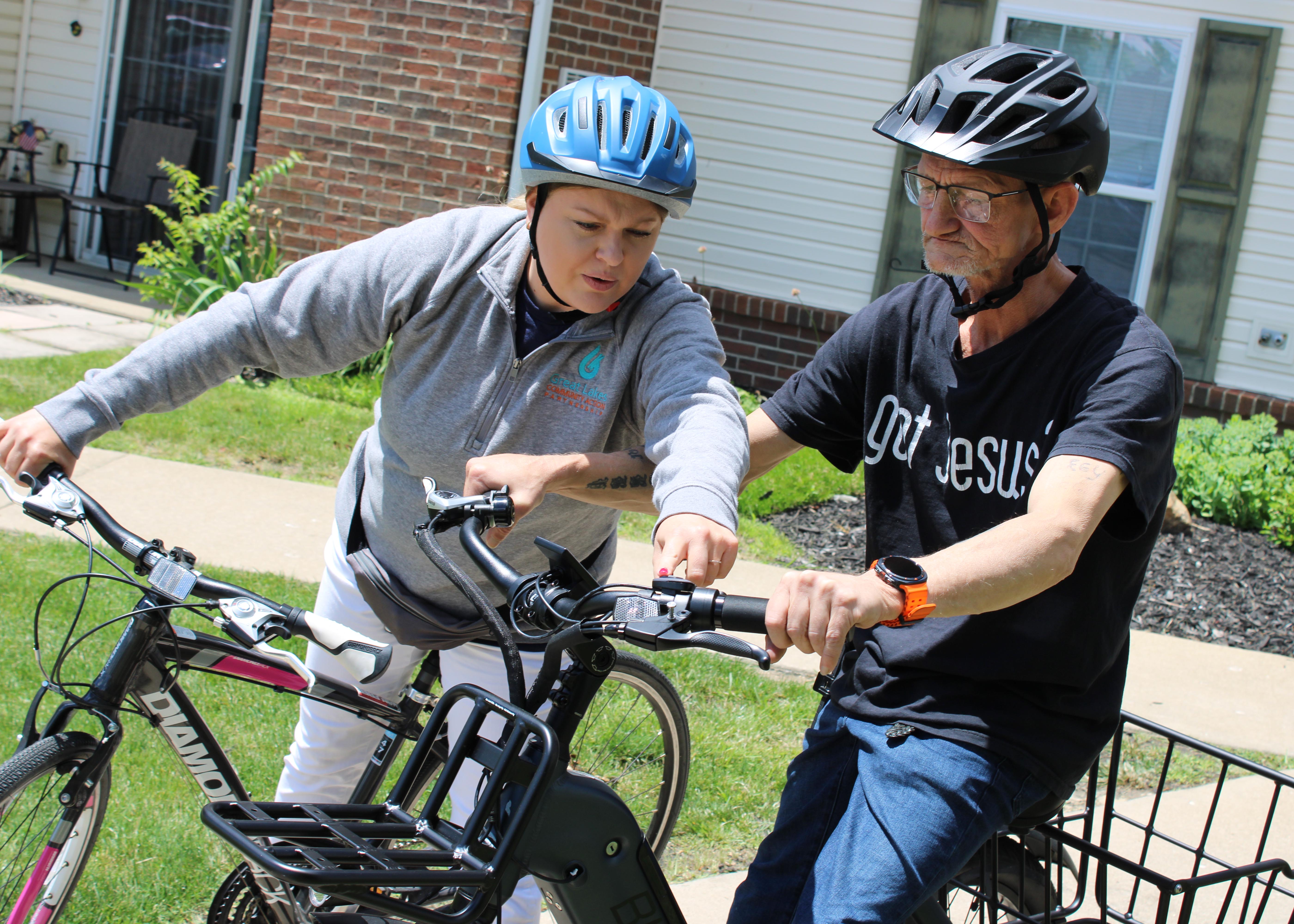 Mobility Management Coordinator Mindy Birkholz points to the brake on the bike for a senior as she provides a safety demonstration