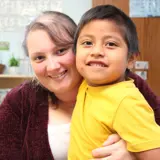 Child and staff member smiling in classroom