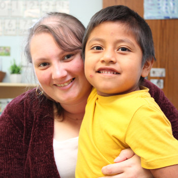Child and staff member smiling in classroom