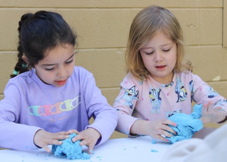 Two children playing with clay at a table.