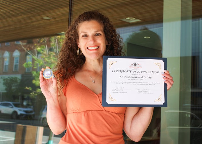 SSVF Family Advocate Katrina Ross holding her certificate of appreciation and a commemorative coin