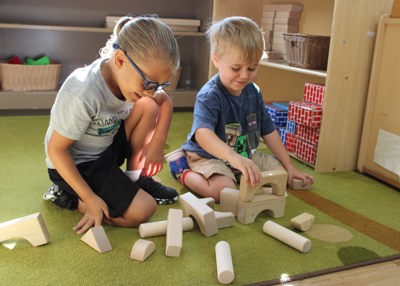 A boy and a girl play with building blocks on the floor of a Head Start classroom